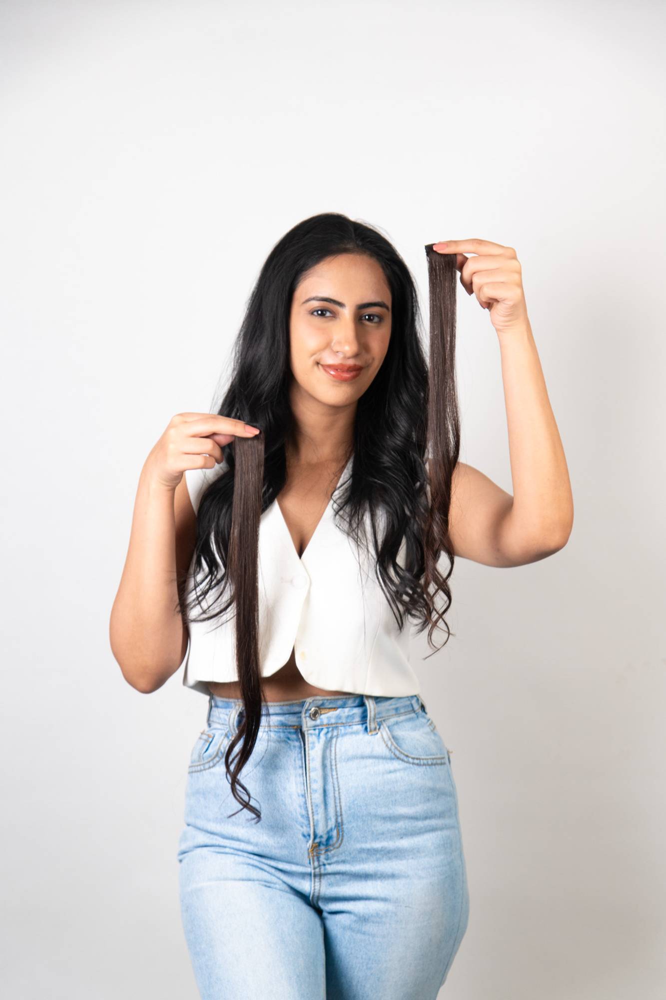 Model Holding Dolcy Dark Brown Clip-In Hair Streaks at Asymmetric Heights – Both Hands Displaying Two Streaks at Full Length Showing Deep Rich Dark Brown Colour and Smooth Human Hair Texture