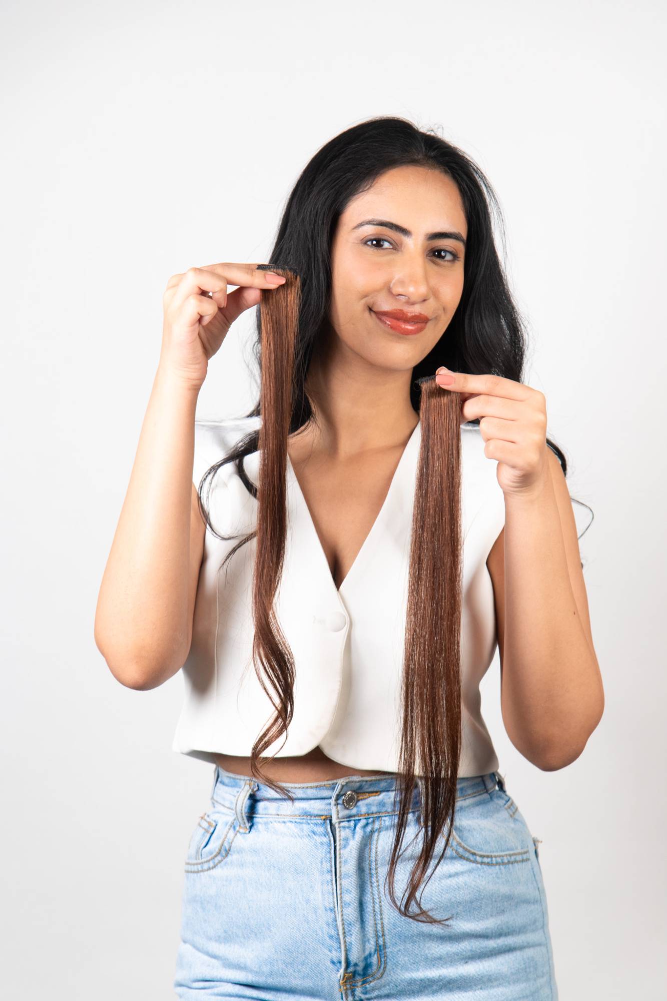 Model Holding Dolcy Light Brown Clip-In Hair Streaks at Face Level – Lifestyle Shot Showing Rich Warm Brown Streak Colour Contrasting Beautifully Against Natural Dark Hair