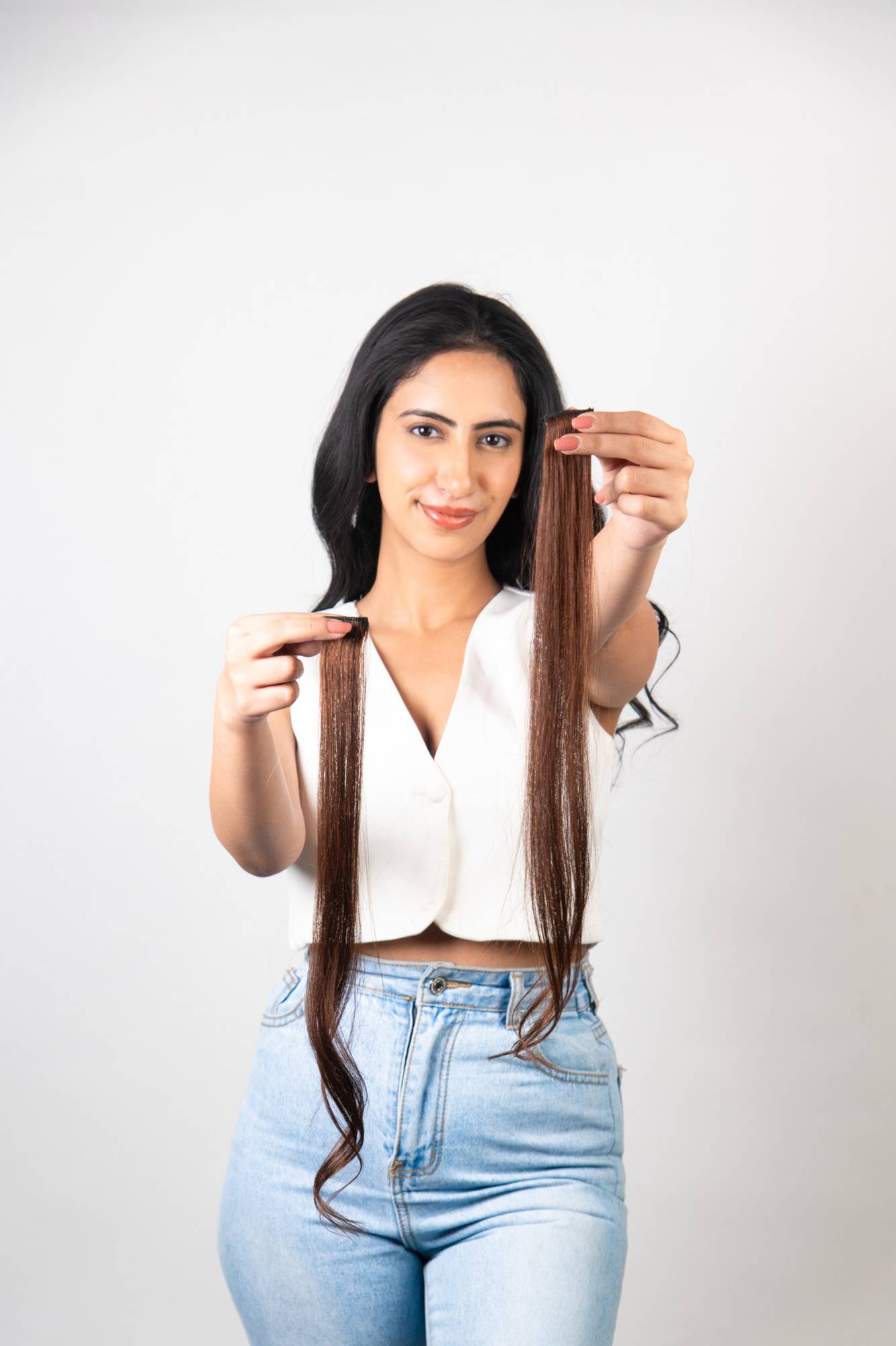 Model Holding Dolcy Light Brown Clip-In Hair Streaks – Both Hands Displaying Two Streaks at Full Length Showing Warm Chestnut Brown Colour and Smooth Human Hair Texture
