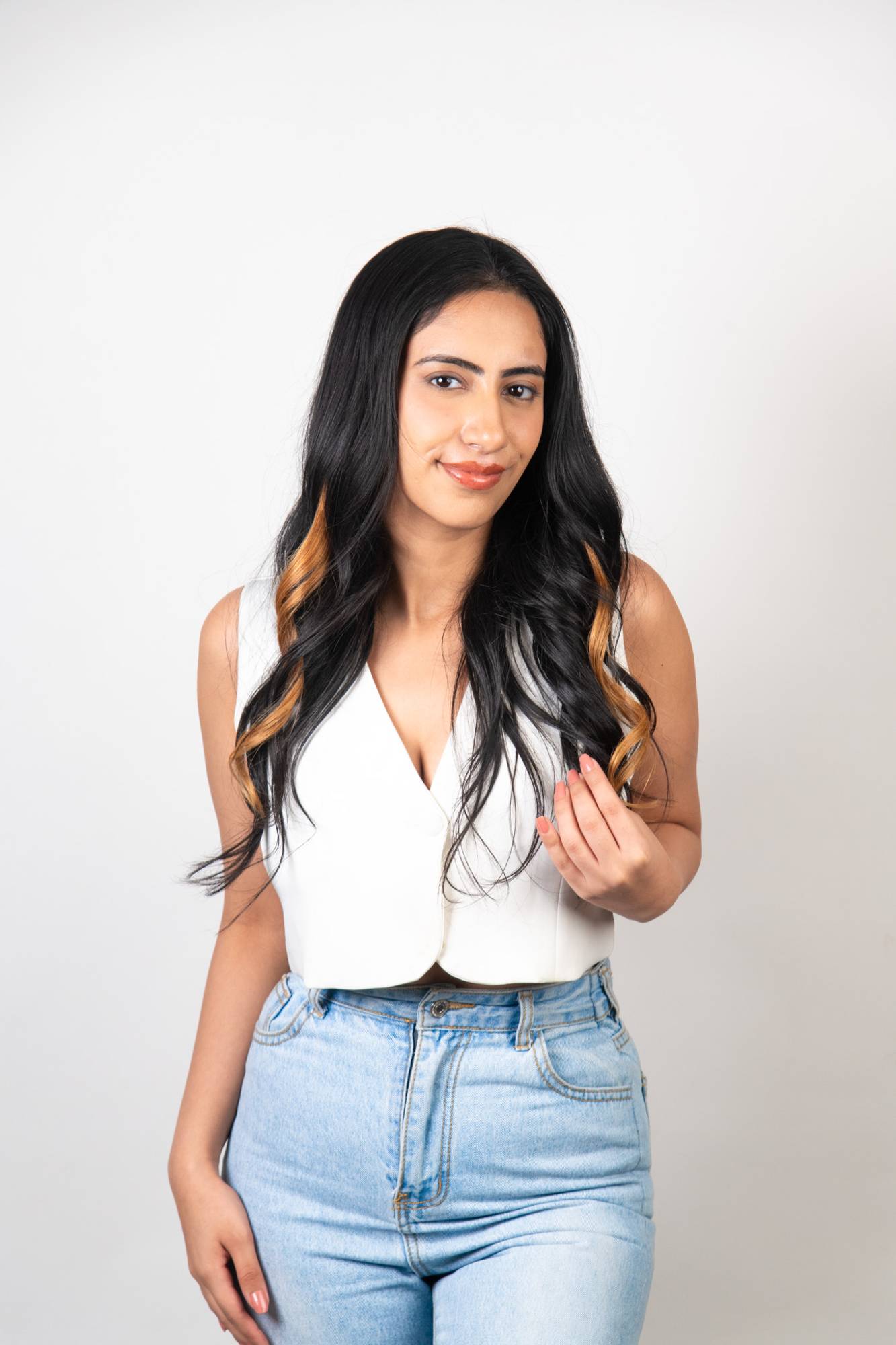 Model with long dark black wavy hair wearing Dolcy Blonde Clip-In Hair Streaks – warm golden blonde highlights seamlessly blended at the ends for a sun-kissed look
