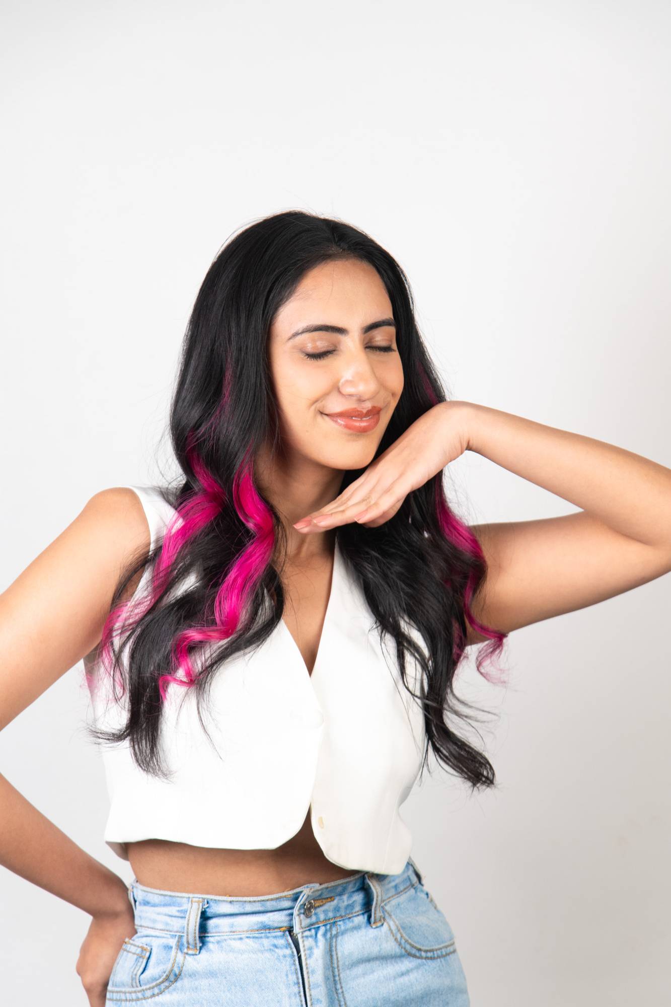 Indian model in elegant pose wearing Dolcy Neon Pink Clip-In Hair Streaks – vibrant electric pink highlights curling through long black wavy hair for a bold statement look