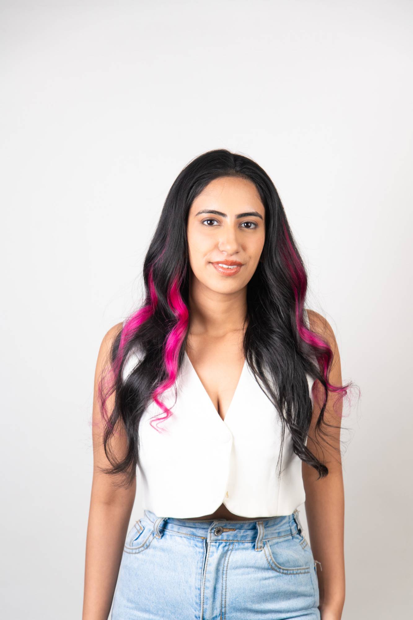 Front view of Indian model with Dolcy Neon Pink Clip-In Hair Streaks – bold electric pink color streaks blended into long dark black wavy hair, no dye no damage
